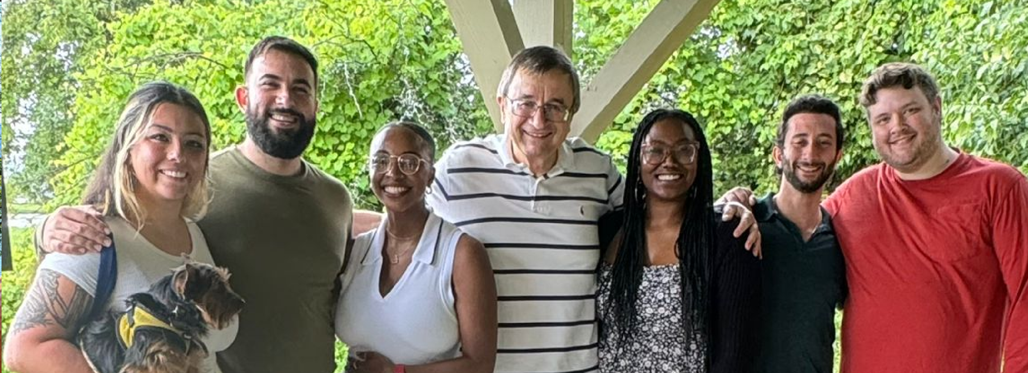 A group of residents smile for a picture in a woodsy setting